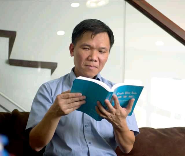 Anh Hanh đang đọc cuốn sách Chuyển Pháp Luân - cuốn sách chính chỉ đạo việc tu luyện.